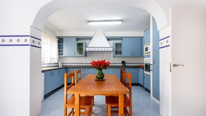A kitchen with a wooden table, blue cabinets, and a white door. - Air-Conditioned Villa "Mascota Rincón de la Victoria" with Pool, Garden & Wi-Fi (Rincón de la Victoria)