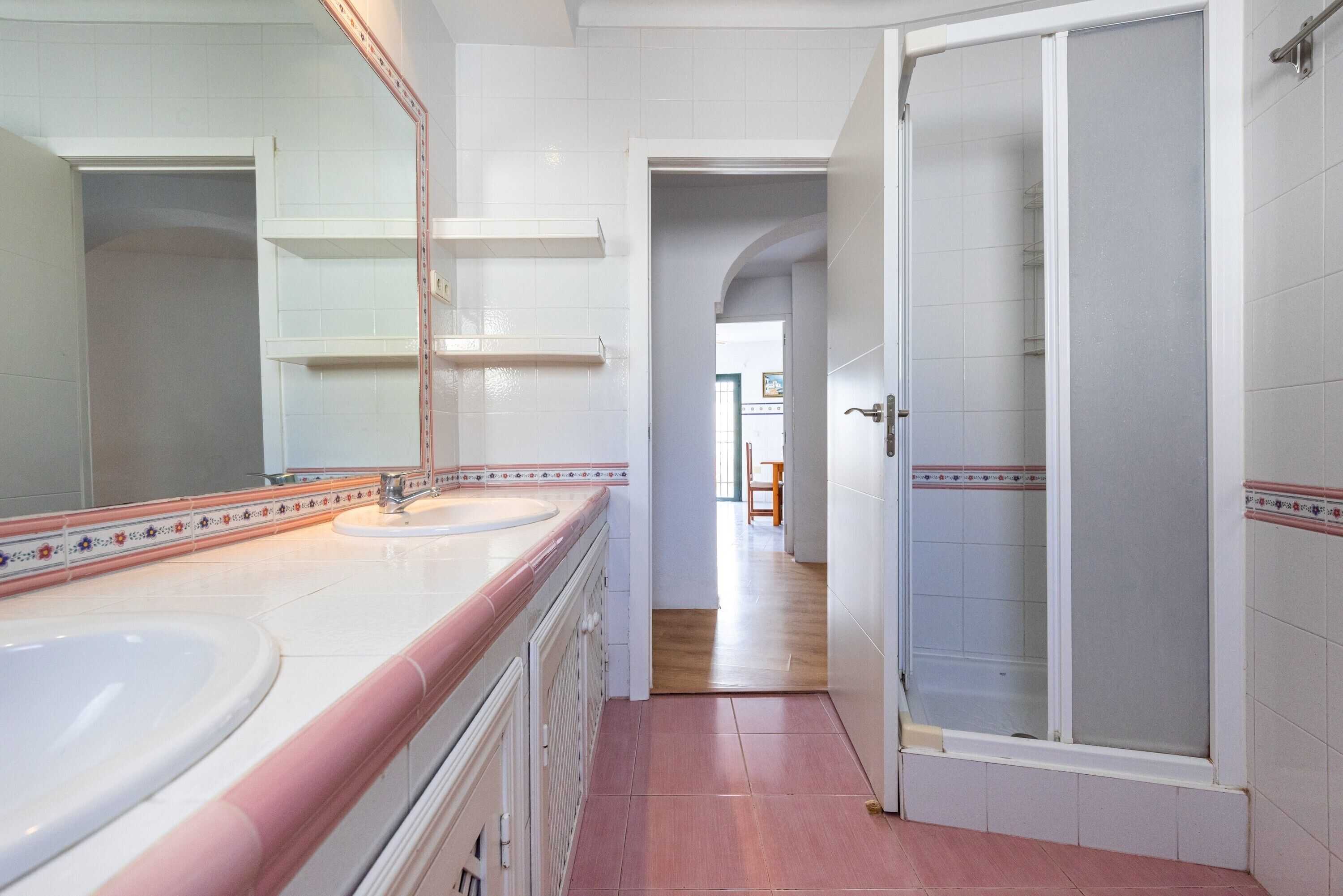 Een badkamer met een grote spiegel, een wastafel en een douche.