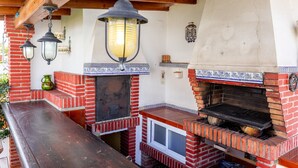 A brick-built outdoor kitchen with a grill, hanging lanterns, and a tiled backsplash. - Air-Conditioned Villa "Mascota Rincón de la Victoria" with Pool, Garden & Wi-Fi (Rincón de la Victoria)