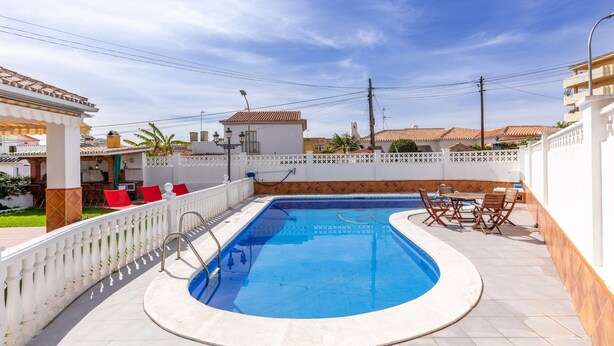 A swimming pool with a white fence, red chairs, and a tiled deck. - Air-Conditioned Villa "Mascota Rincón de la Victoria" with Pool, Garden & Wi-Fi (Rincón de la Victoria)