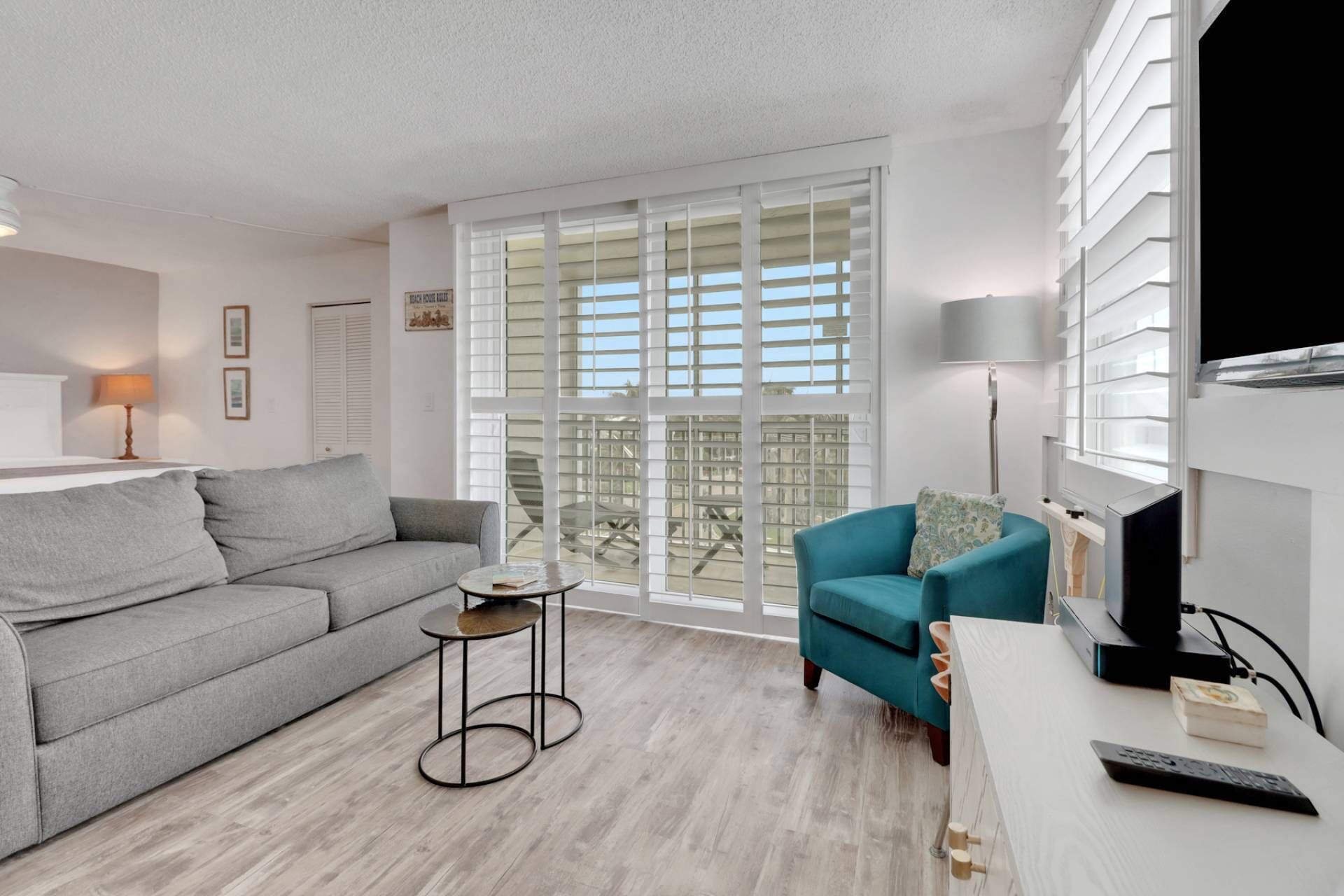 A modern living room with a grey sofa, teal armchair, and a small round table.