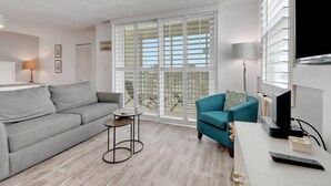 Un salon moderne avec un canapé gris, un fauteuil turquoise et une petite table ronde.