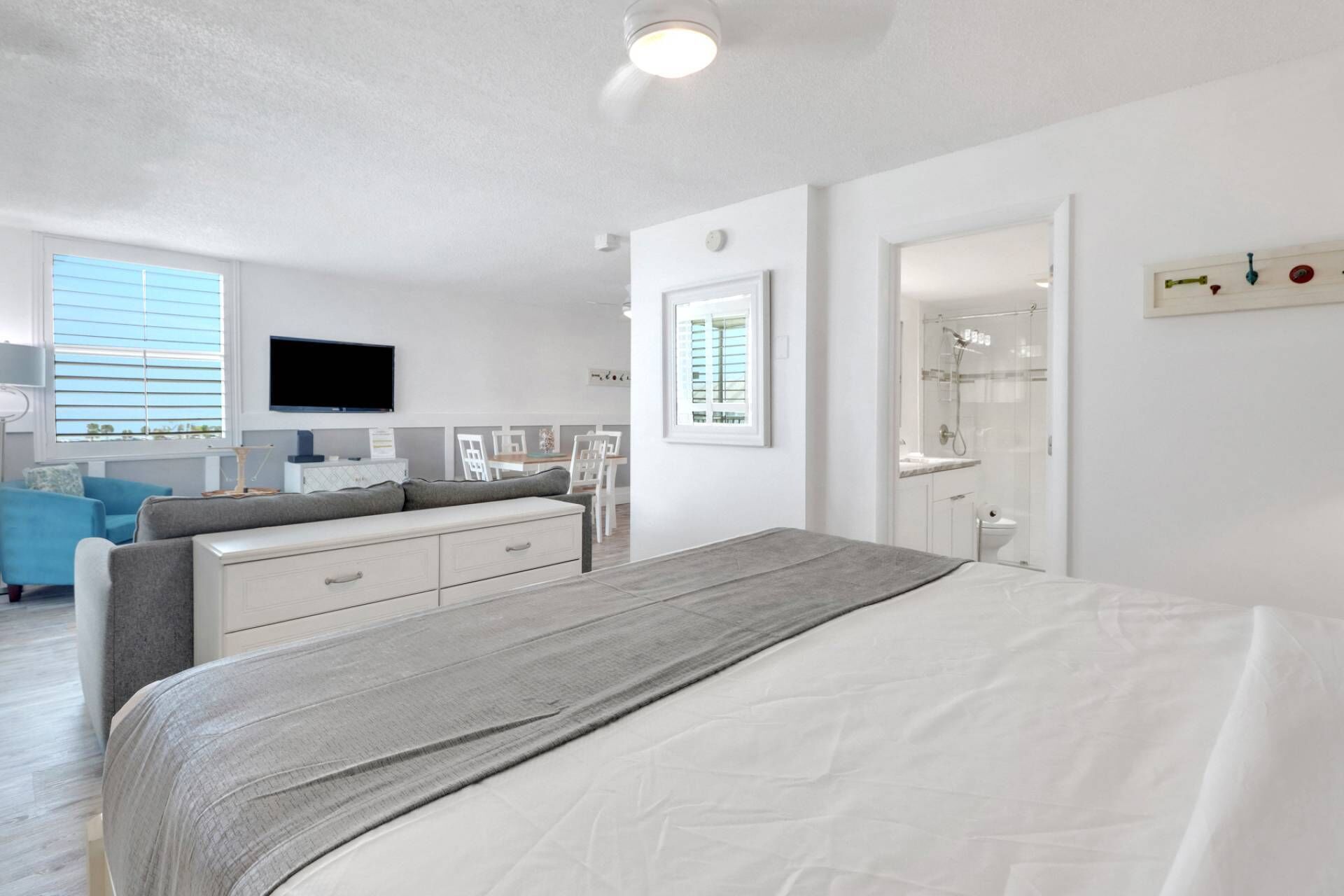 Un dormitorio moderno con cama, televisión, escritorio y baño.