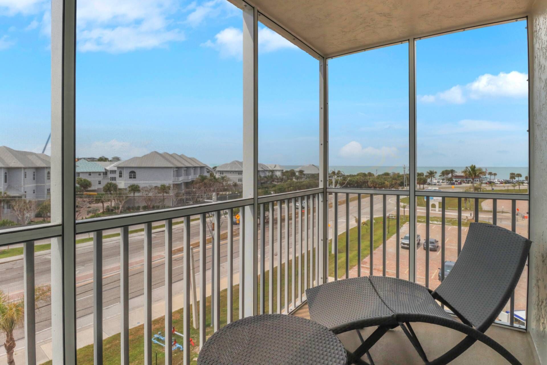 A balcony with two chairs and a view of a road and buildings.