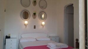 Une chambre à coucher comprenant un lit, deux tables de chevet, une commode, un miroir et des lampes fixées au mur.