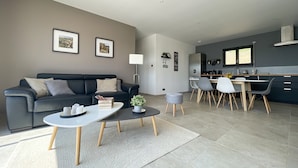 En moderne stue med sofa, sofabord og spiseområde med stole og bord.