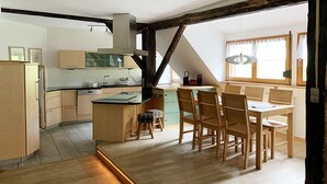 A modern kitchen with wooden cabinets, a central island, and a dining area with wooden chairs. - Fewo 7 - Hauptmann (Todtnau)