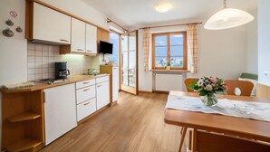 Une cuisine avec des meubles en bois, une machine à café et un coin repas comprenant une table et des chaises.