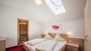 Un dormitorio con un tragaluz, una cama con almohadas, una mesita de noche y un armario de madera.