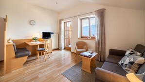 Ein modernes Wohnzimmer mit einer Couch, einem Esstisch, einem Fernseher und Blick ins Freie.