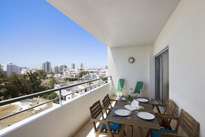 A balcony with a table set for two, chairs, a potted plant, and a view of the cityscape. - Apartment Villa Rosa with A/C, Wi-Fi, Terrace and Balcony (Portimão)
