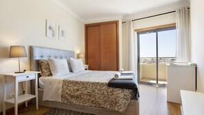 A bedroom with a bed, bedside tables, a window, and a balcony.