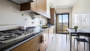 A modern kitchen with a gas stove, wooden cabinets, and a view to the balcony.