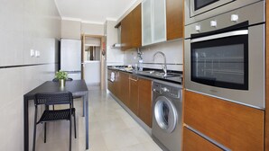 A modern kitchen with stainless steel appliances, a built-in oven, and a washing machine.