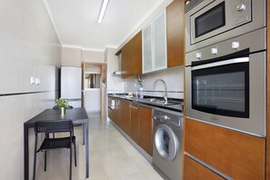 Une cuisine moderne équipée d’appareils électroménagers en acier inoxydable, d’un four encastré et d’un lave-linge.