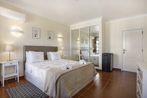 A hotel room with a bed, bedside tables, a wardrobe, a mirror, and a trash bin.