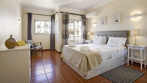A hotel room with a bed, bedside tables, a desk, a chair, a window with curtains, and artwork on the wall. - Estrela do Vau Apartment with Sea View, Pool, A/C, Wi-Fi, Garden, Terrace and Balcony (Portimão)