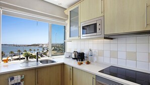 Cozinha com vista para o mar, micro-ondas e fogão.