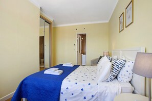 Una habitación de hotel con una cama, una mesita de noche, una lámpara y una puerta que da a un baño.