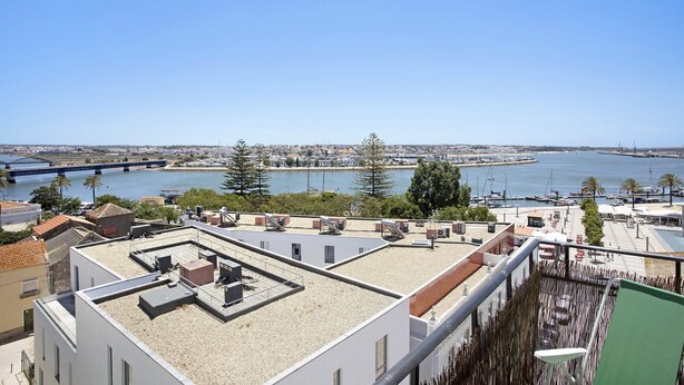 Terraço no telhado com vista para uma marina e uma ponte.