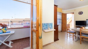 A room with a dining table, chairs, a TV, and artwork on the wall. - Vacation Apartment Casa Rita with Balcony & A/C (Castelsardo)