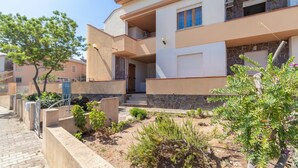 A residential building with a stone facade, a balcony, and a small garden area with various plants. - Vacation Apartment Casa Rita with Balcony & A/C (Castelsardo)