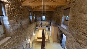 A stone-walled room with a wooden ceiling, a kitchen area with modern appliances, and a bench. - Pet-friendly Vacation Home Villae Carreiro with Pool, A/C, Wi-Fi, Garden & Terrace (Braga)