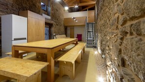 A rustic interior with a wooden table and benches, stone walls, and a modern kitchen. - Pet-friendly Vacation Home Villae Carreiro with Pool, A/C, Wi-Fi, Garden & Terrace (Braga)