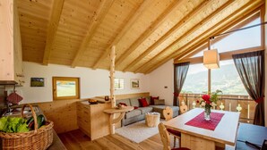 Un interior de madera con sofá, mesa de comedor y vistas amplias a través de grandes ventanales.