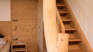 Una escalera de madera en una habitación con una cama y una mesita de noche.