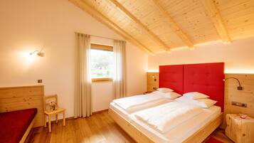 Ein Zimmer mit Holzrahmen, einem großen Bett, einem Sessel und einem Fenster mit Vorhängen.