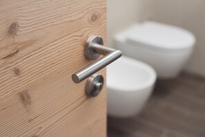 Eine Holztür mit einem modernen Griff, einem sichtbaren Schloss und einer weißen Toilette im Hintergrund.