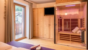 Huoneessa on sänky, liukuovella varustettu lasiterassi, puinen sauna ja televisio.