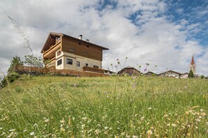 Un immeuble à plusieurs étages doté de balcons, une enseigne indiquant « Appartements », et une tour en arrière-plan.