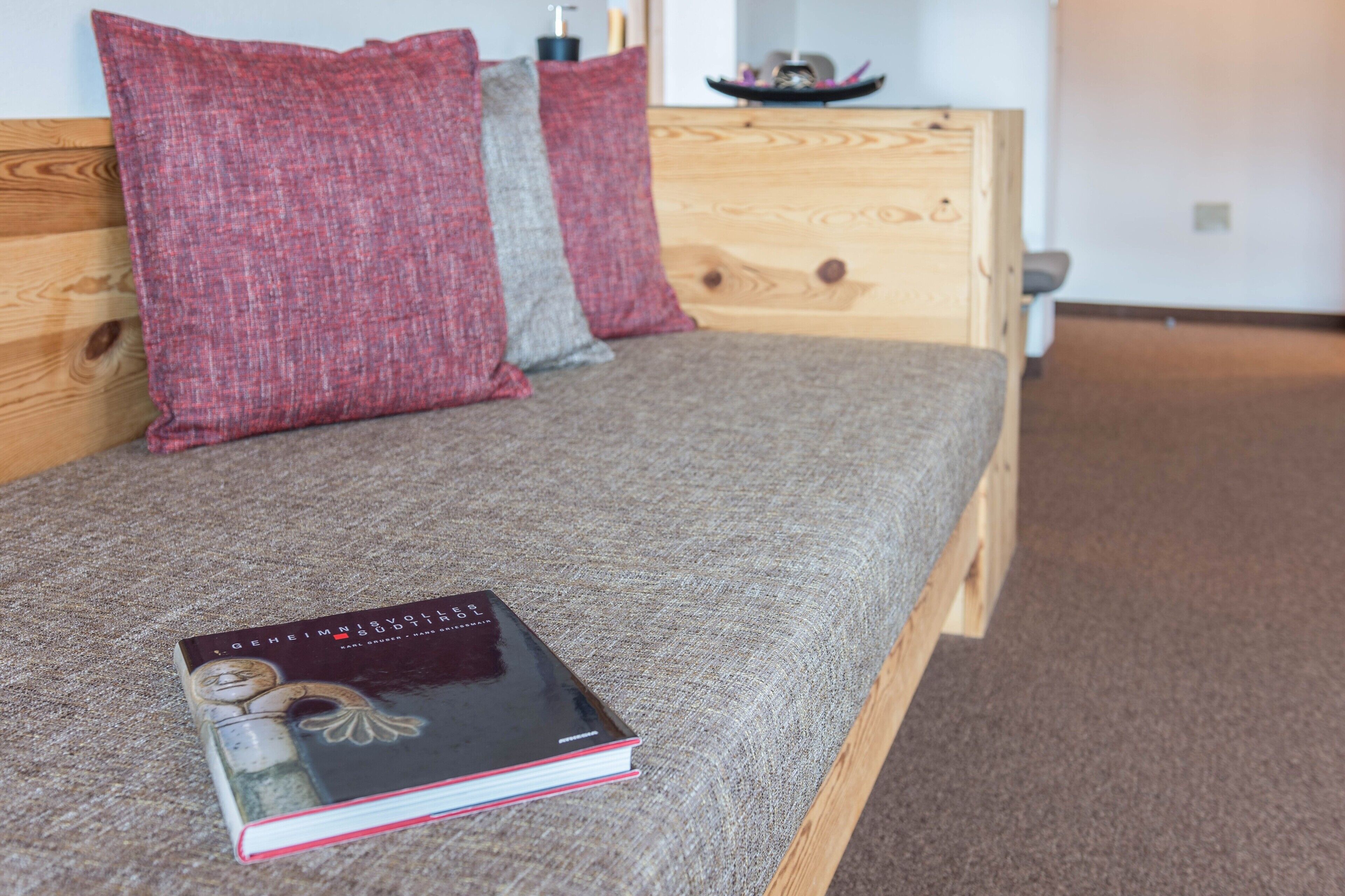 Un lit avec un livre, des oreillers et une tête de lit en bois, dans une chambre.