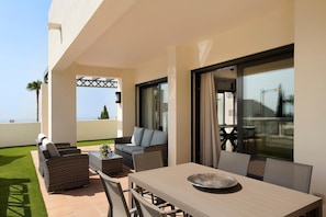 Eine Terrasse im Freien mit Esstisch, Stühlen und einer Couch.