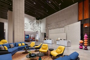 En rummelig lobby med reception, siddeområde og dekorativ belysning.
