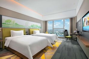 A hotel room with two beds, a desk, a chair, a TV, and a large window with a city view.