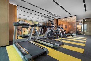 Et moderne fitnesscenter med løbebånd, crosstrainere og spinningcykler.