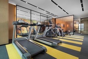Un gimnasio moderno con cintas de correr, elípticas y bicicletas estáticas.