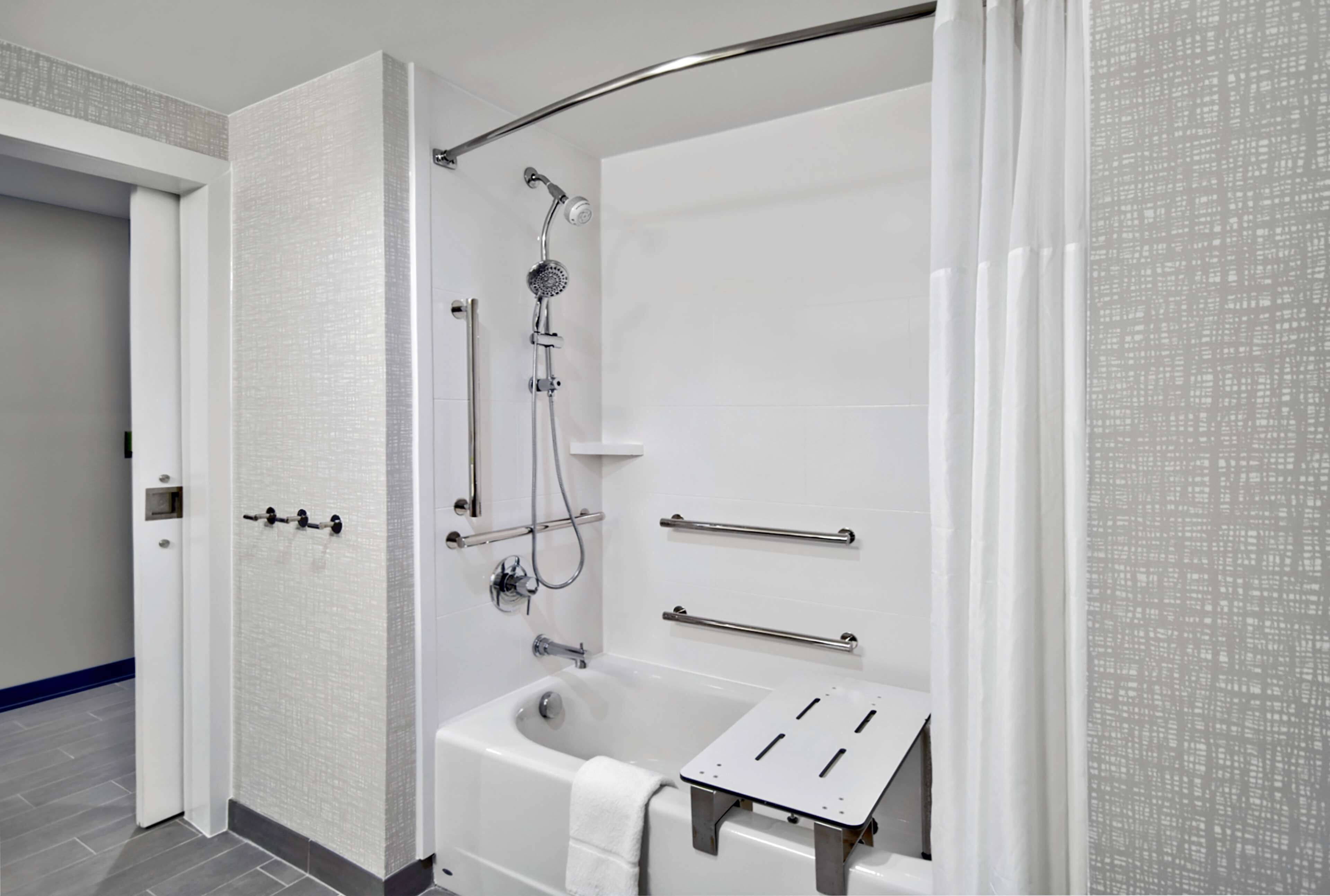 A modern bathroom with a walk-in shower, a bathtub with a grab bar, and a towel rack.