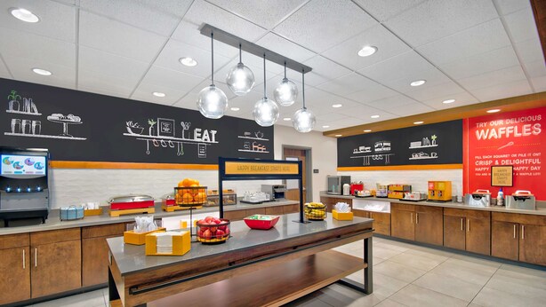 Un espace réservé au petit-déjeuner, avec un comptoir, divers aliments et un panneau publicitaire pour des gaufres.