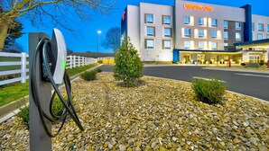 Un hôtel moderne, doté d’une enseigne bien visible, d’une cour en gravier bien entretenue et offrant une vue sur un ciel dégagé.