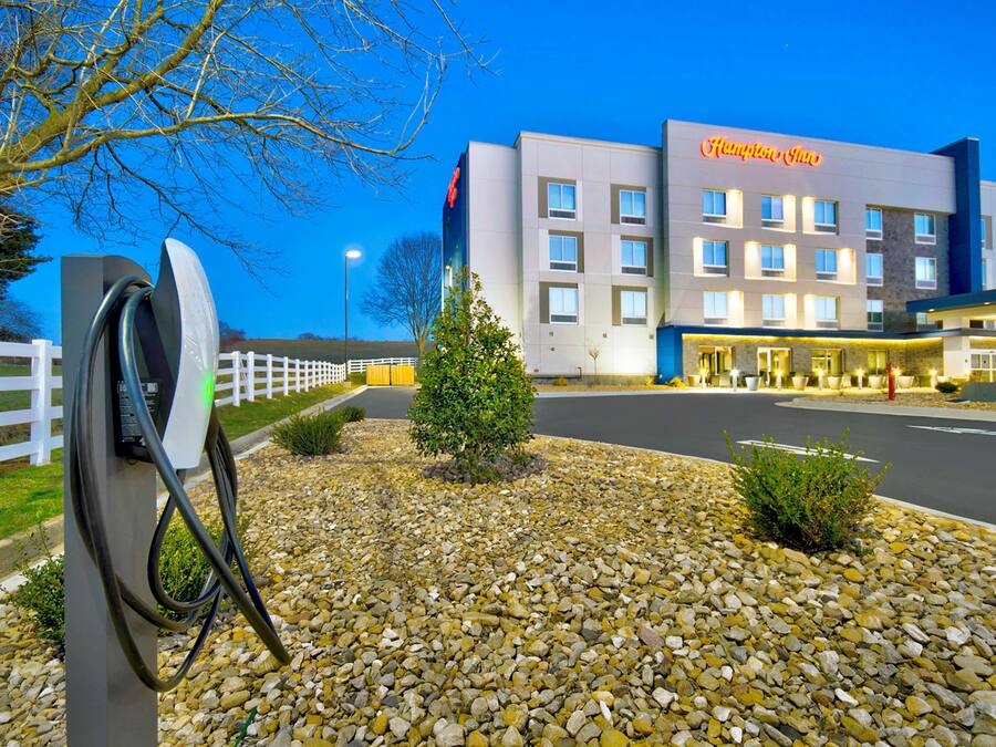 A modern hotel with a prominent sign, a well-maintained gravel area, and a clear sky.