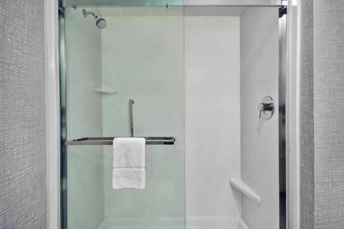A glass-enclosed shower with a towel rack and a visible showerhead.