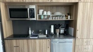 Una cucina moderna con mobili in legno, un forno a microonde in acciaio inox, una lavastoviglie e un piano di lavoro con diversi utensili da cucina.