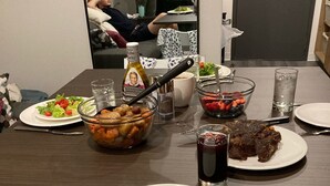 Una tavola imbandita con diversi piatti, tra cui un'insalata, un'anguria e altri frutti, e un piatto di carne. Ci sono anche bicchieri e posate.