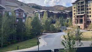 Un hotel moderno con diversi piani, una seggiovia sullo sfondo e un viale curvo.
