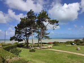 A park with a bench, trees, and a view of the sea. - Gîte Grand Large (Petit-Caux)