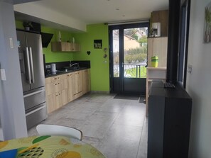 Cocina compacta con refrigerador, lavamanos y armarios de madera.